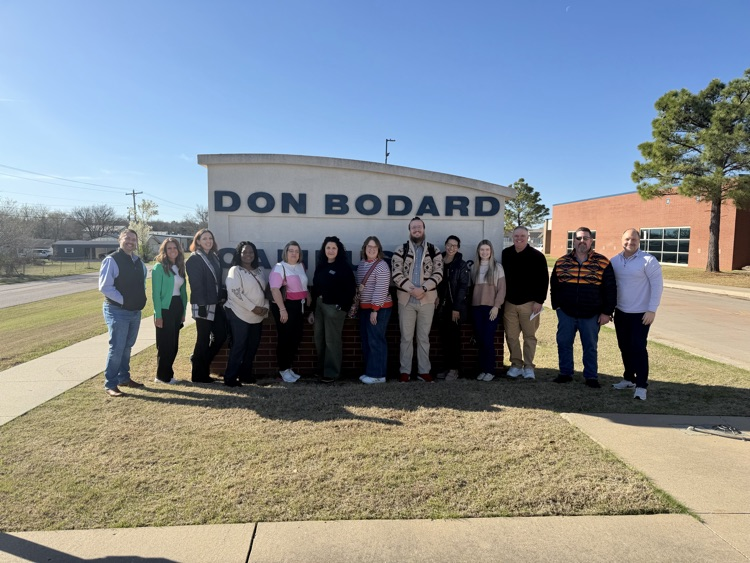 adults standing in front of school sign