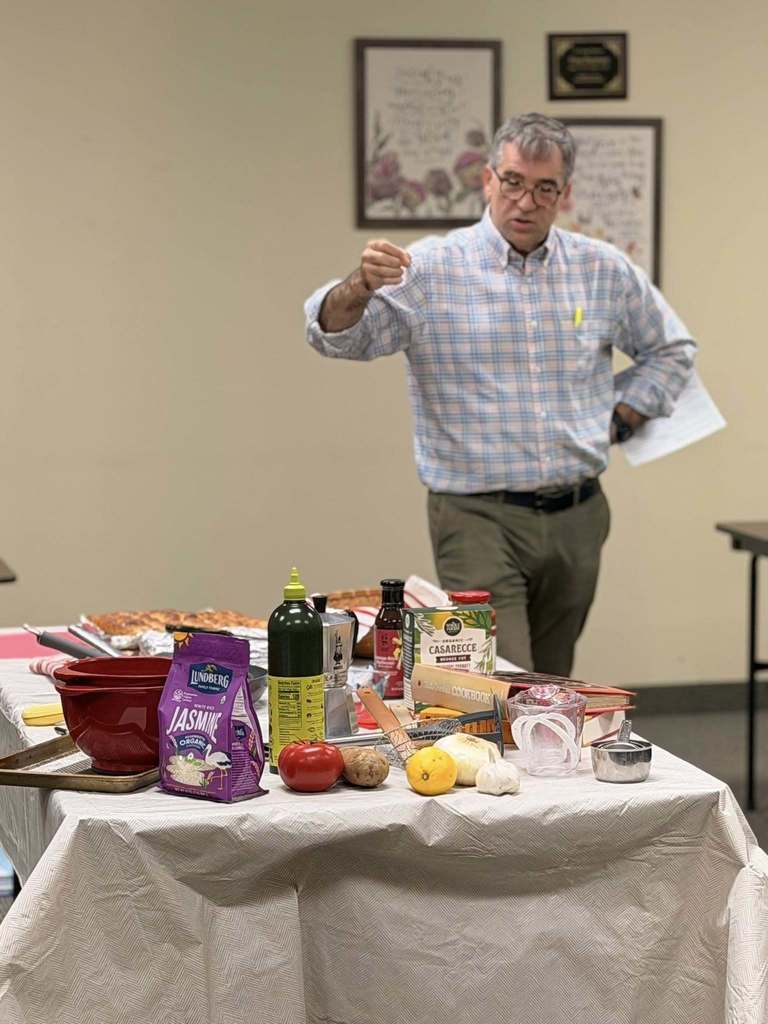 man speaking with a table of food in front of him