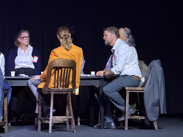 man sitting at table on stage
