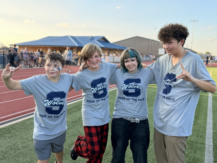 four students standing on football field