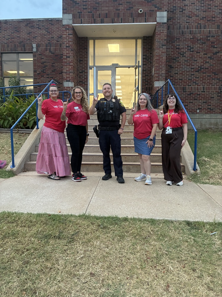 women in matching red shirts standing with officer 