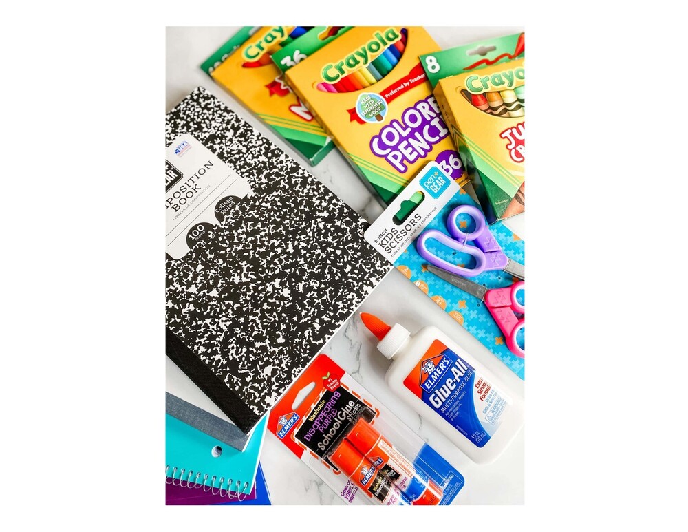 Picture of school supplies: colored pencils, glue, glue sticks, scissors, journal