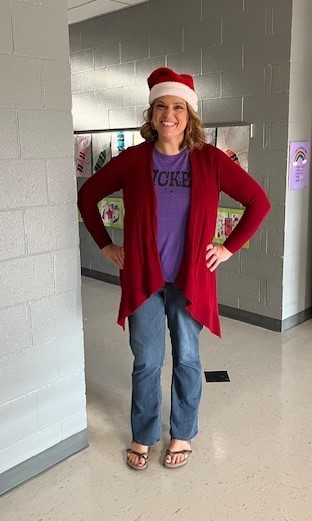 Teacher in hallway wearing red hat and sweater
