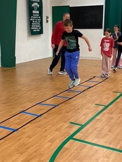 Young boy hoping through agility ladder.