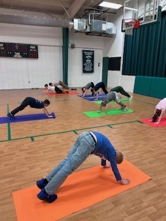 Students doing downward dog on yoga mats.