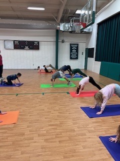 Students doing downward dog on yoga mats.
