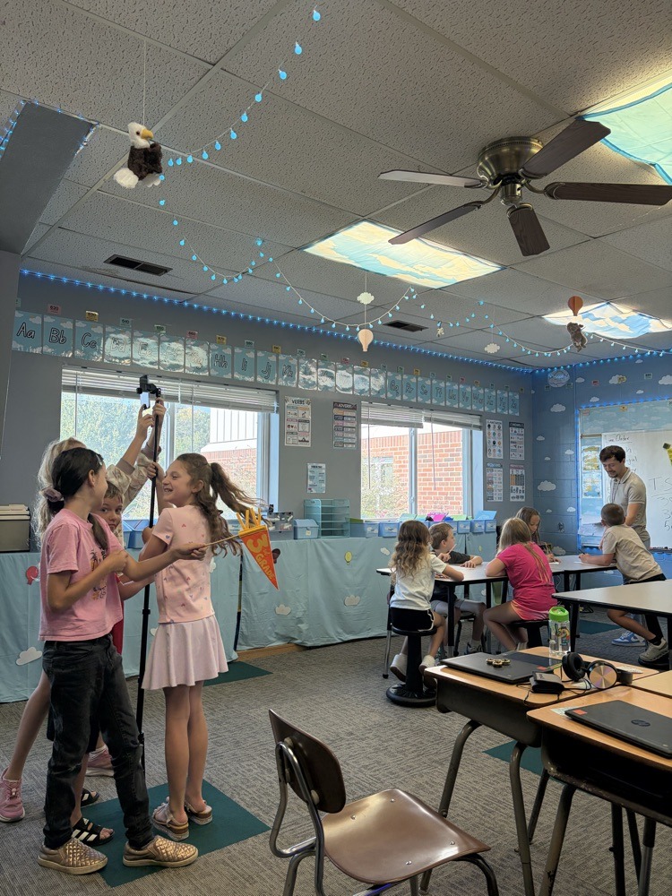 4th Graders holding up fake camera filming 3rd graders.