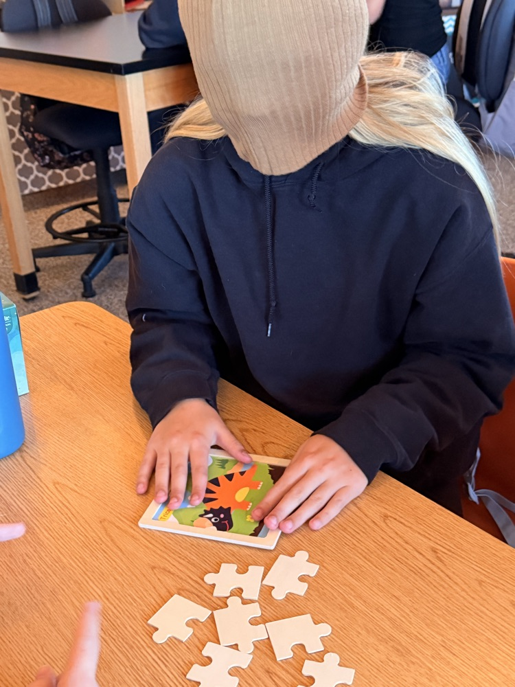 Student putting together a puzzle while blindfolded