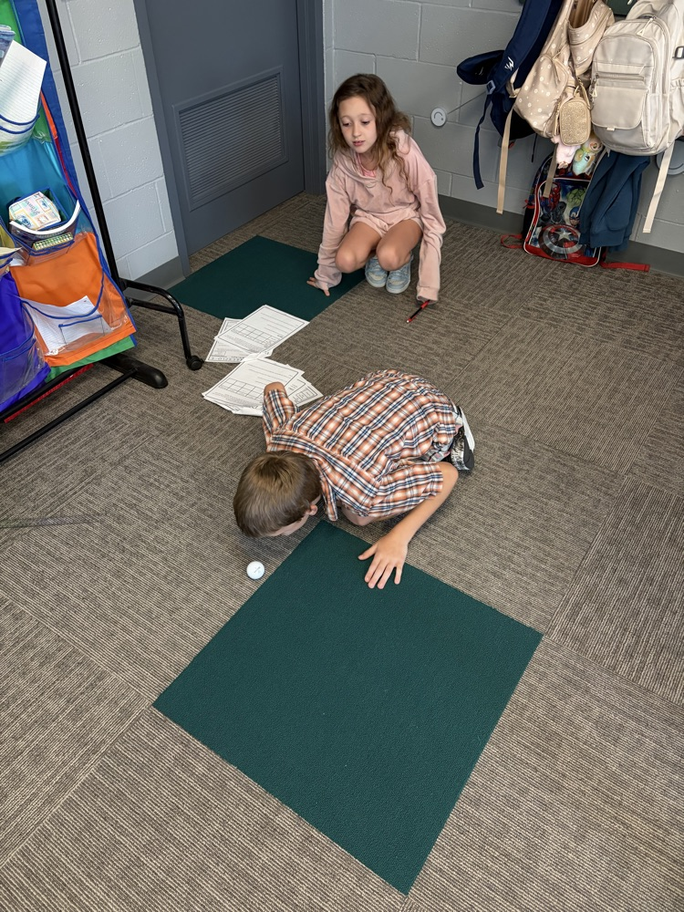 student doing science activity, blowing on a ball