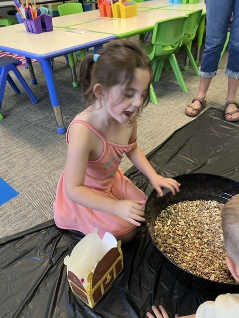 Young student digging in container for treasures.