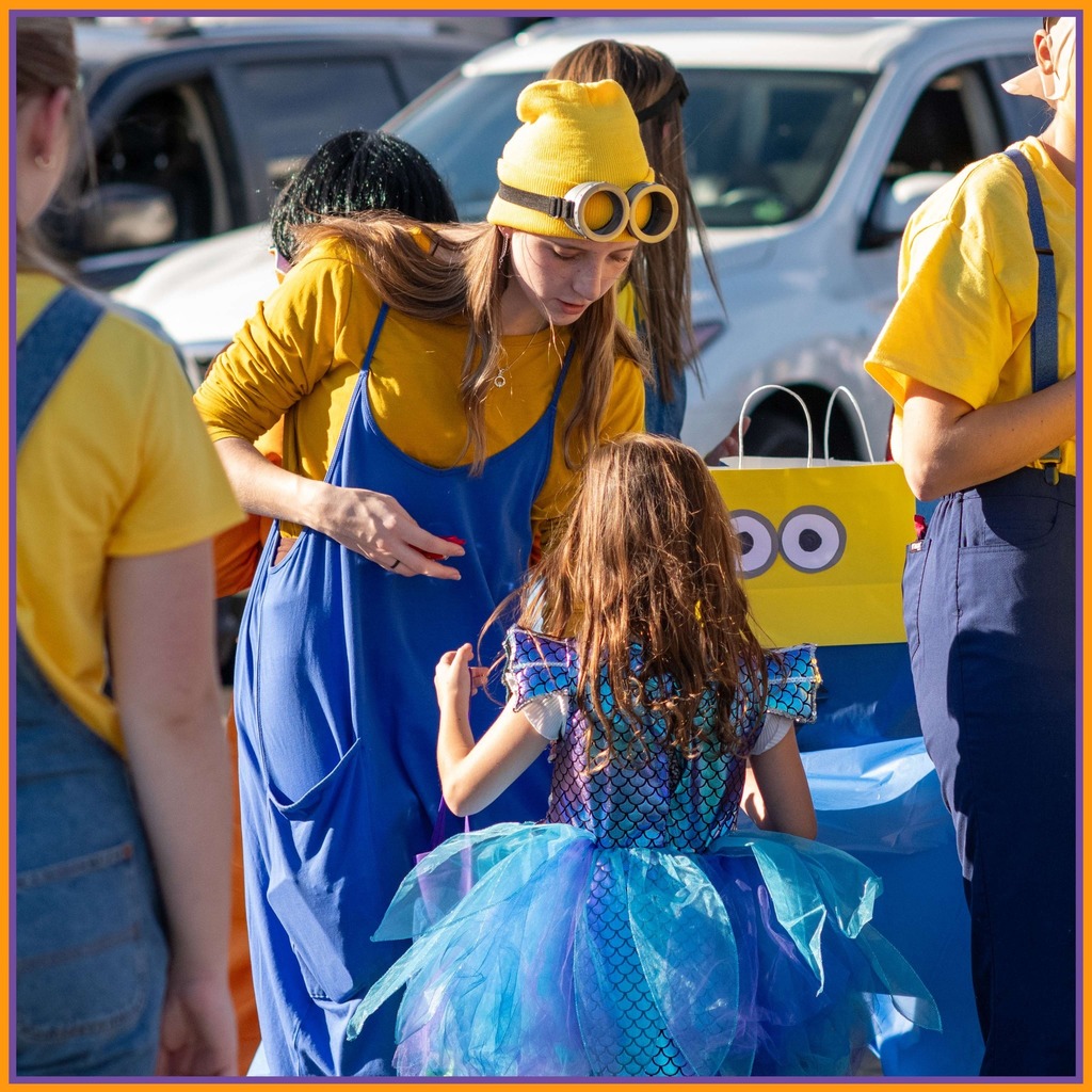 A group of students handing out candy as a minion 