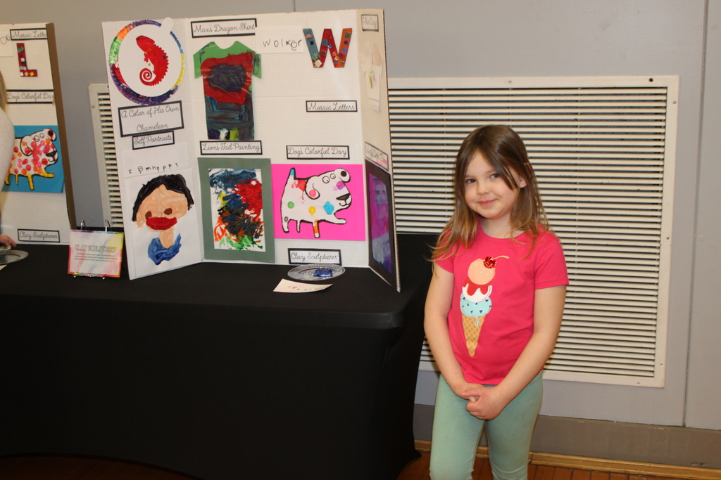 prek student stands in front of trifold art display