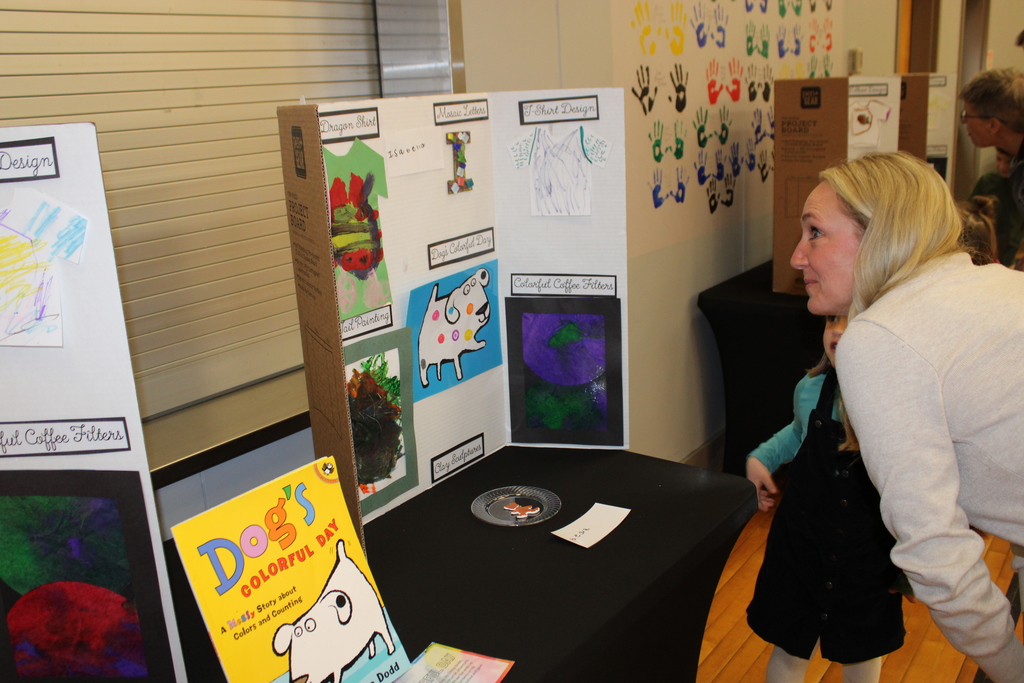 prek student and staff member look at trifold art display