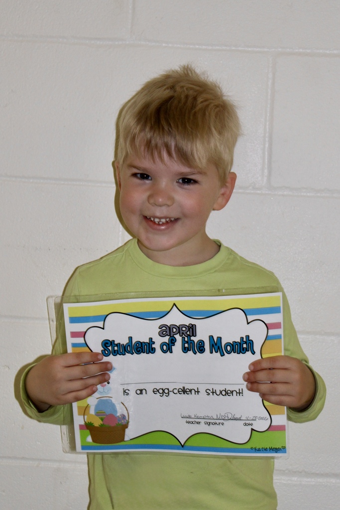 preK male student with blond hair holding a certificate and smiling