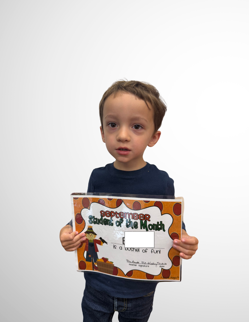 male preschool student holding a certificate and smiling
