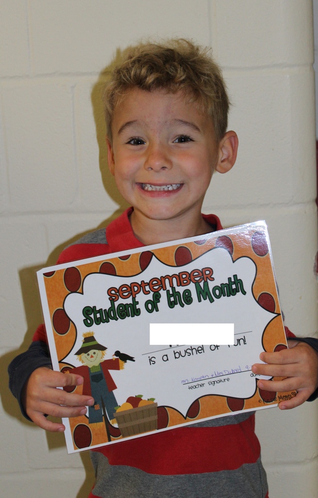 male preschool student holding a certificate and smiling