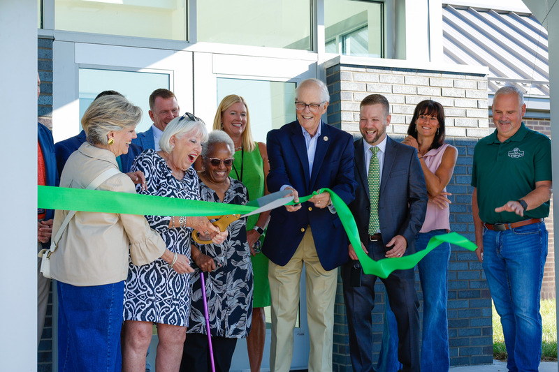 Board Member Joanna Freels cuts the ribbon surrounded by others