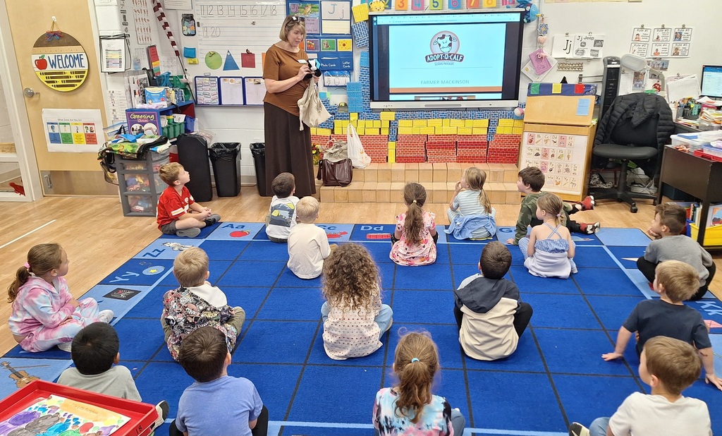 Mrs. Kassel showing Mrs. Larrick's PreK, Journey the stuffed animal dairy calf.