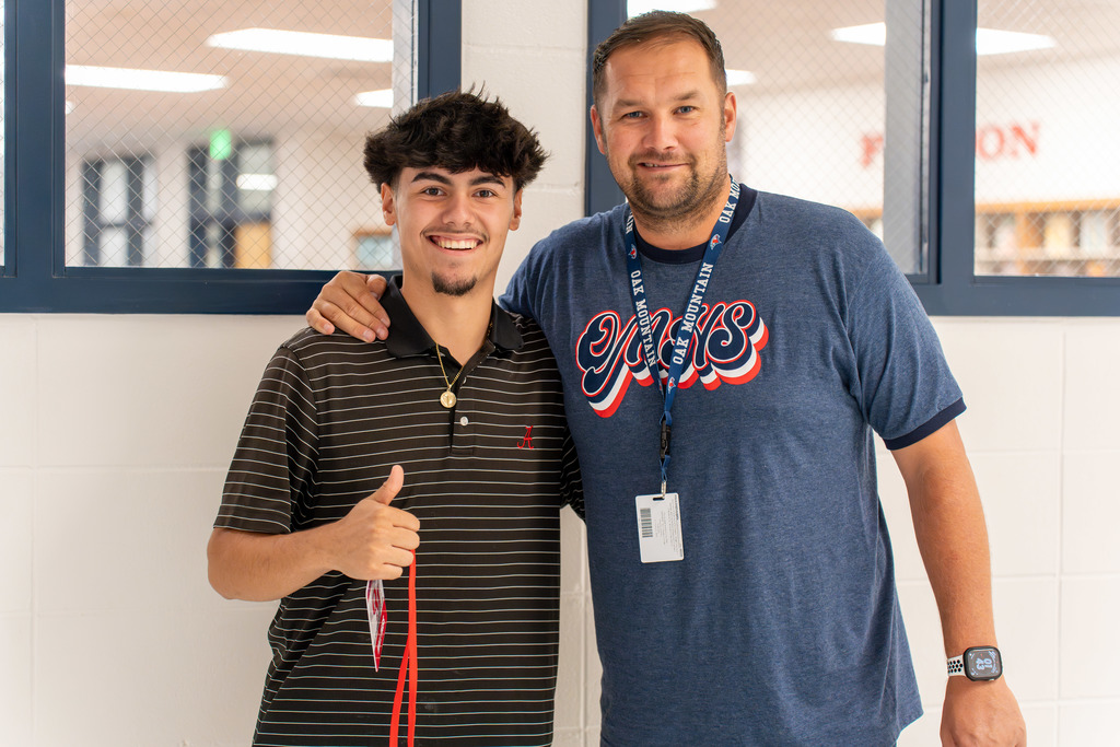 A teacher and student pose for a photo.