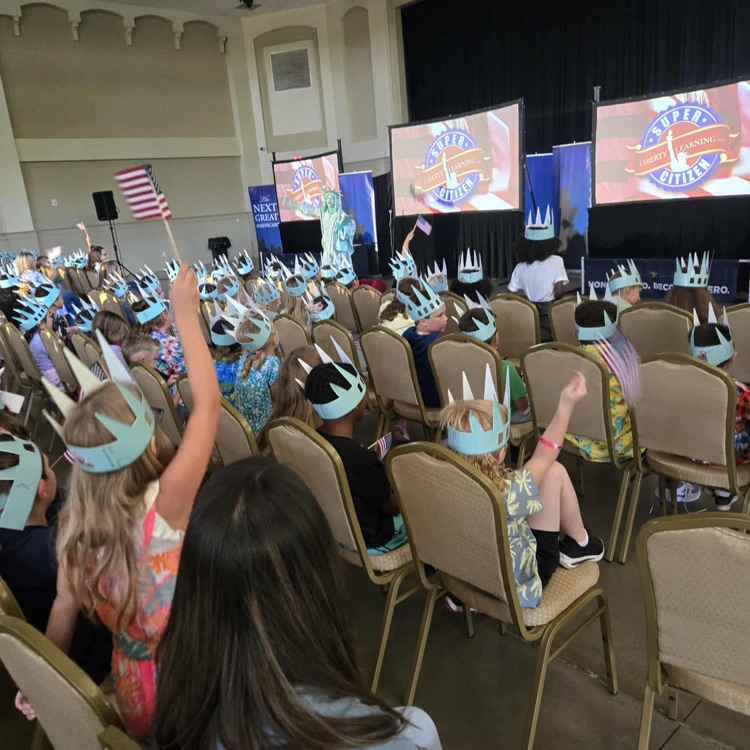 students in lady liberty crowns, waving flags with Libby Liberty