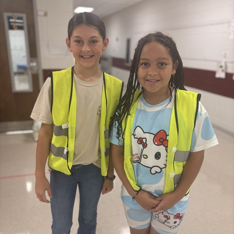 two girls posing with safety vests in the hallway  