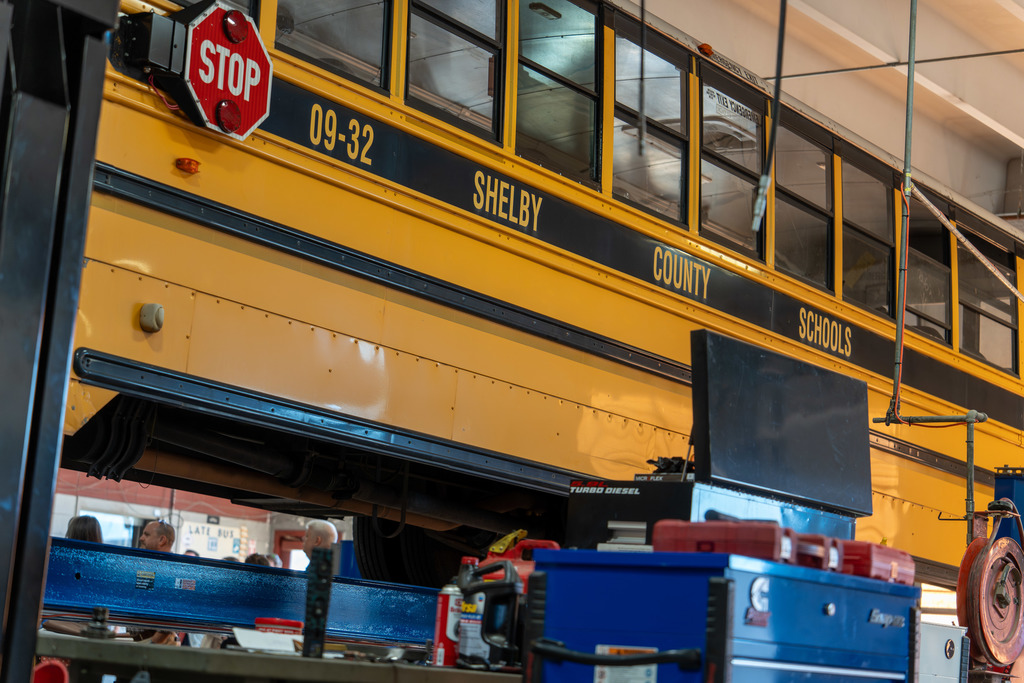 A bus that is lifted at the bus shop.