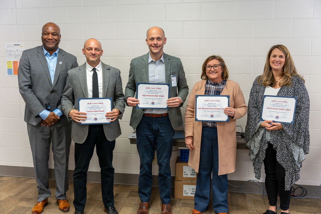 Administrators are recognized for attendance achievements.