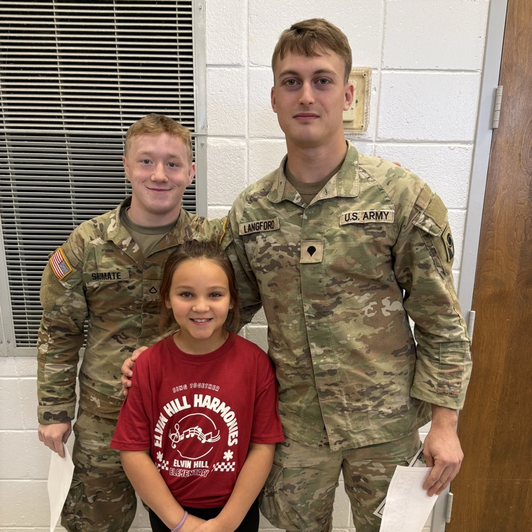 girl poses with two soldiers in army fatigues 
