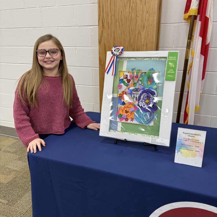 student stands beside original artwork 