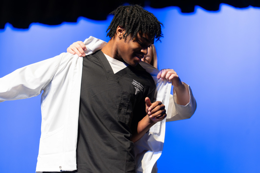 Student receives a white jacket during the ceremony.