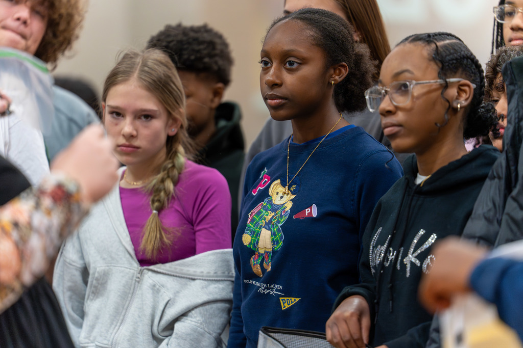 Students listen at one of the informational tables.