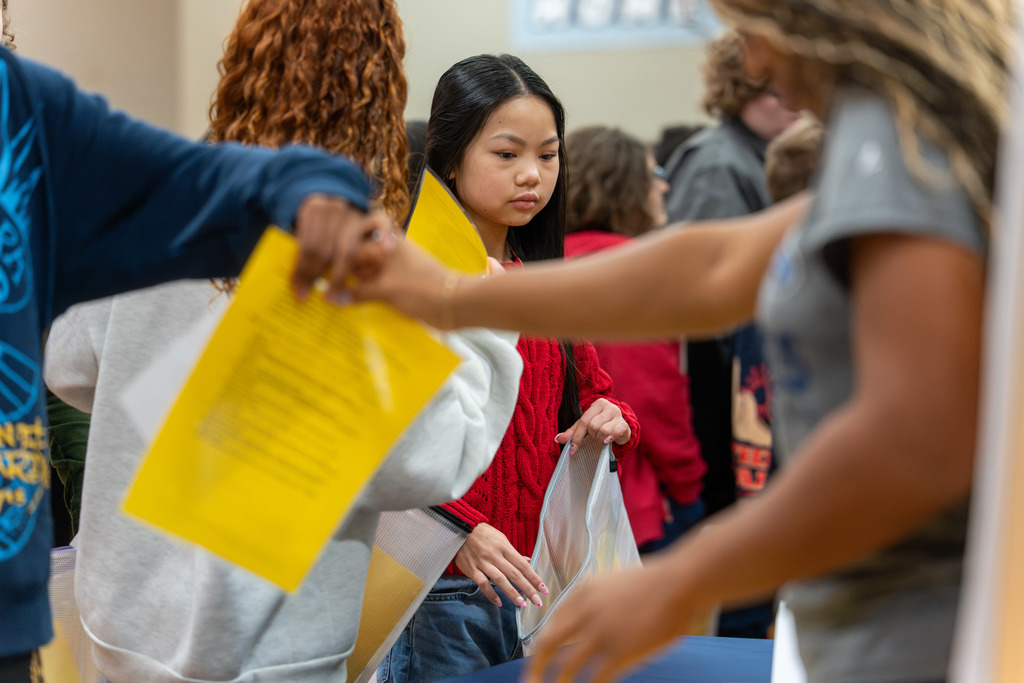 Students receive supplies from a table.