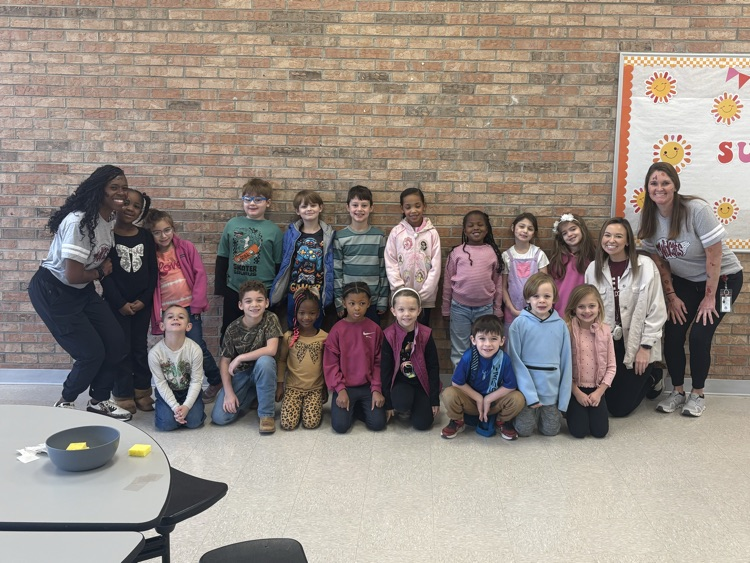 1st grade class posed in front of a brick wall with administrators and teacher  