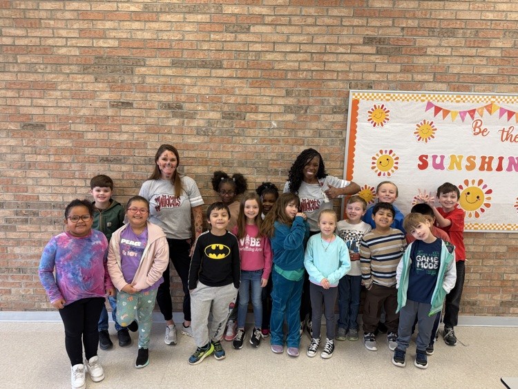2nd grade class posed in front of a brick wall with administrators and teacher  