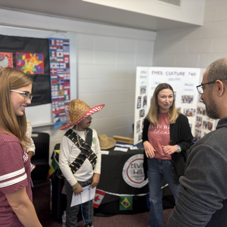 teachers and student speak with visitor at the table 