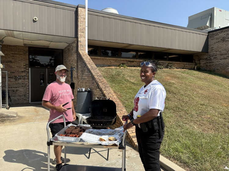 School resource officer, pictured with maintenance tech as they grill, hamburgers, and hotdog