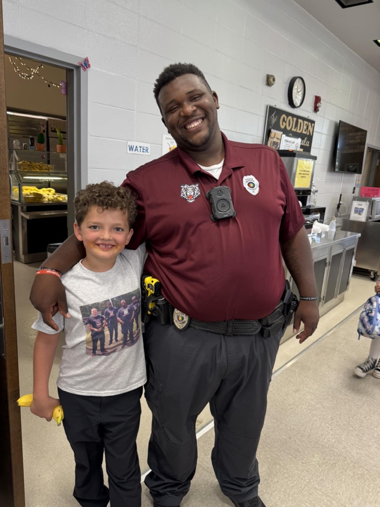 School resource officer pictured with student in the lunchroom serving line
