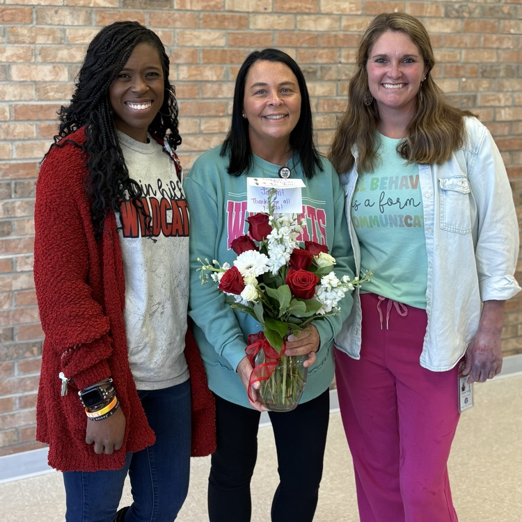 support person of the year holds flowers as she poses with 2 administrators