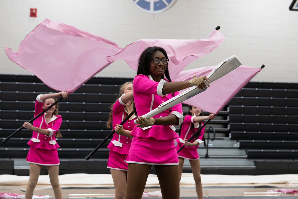 Several students with flags and rifles during Winter guard performance