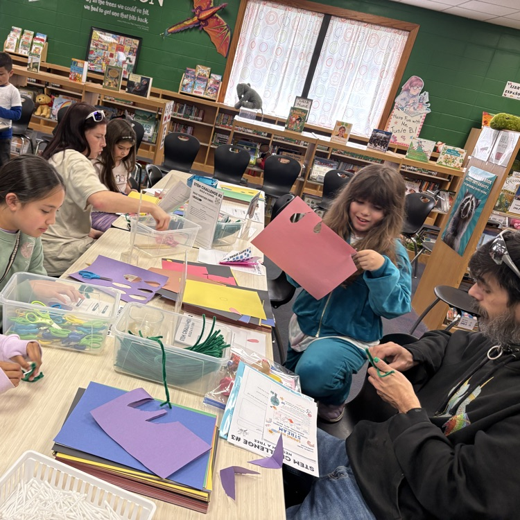 student and families make flowers from pipe cleaner and construction paper 