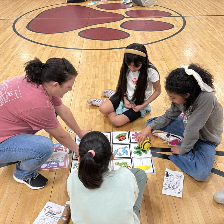 teacher works with 3 students to code beebot robots 
