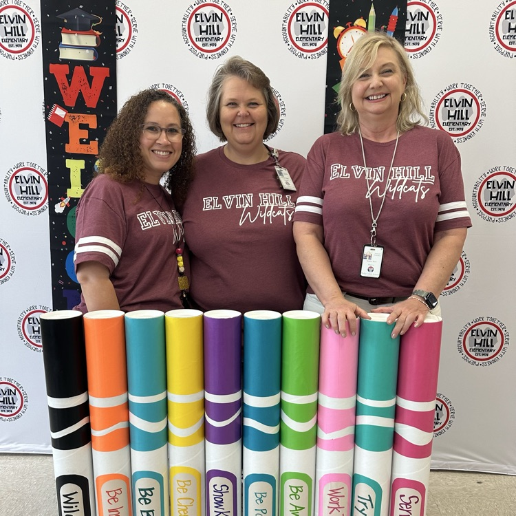 three ladies standing in front of school backdrop