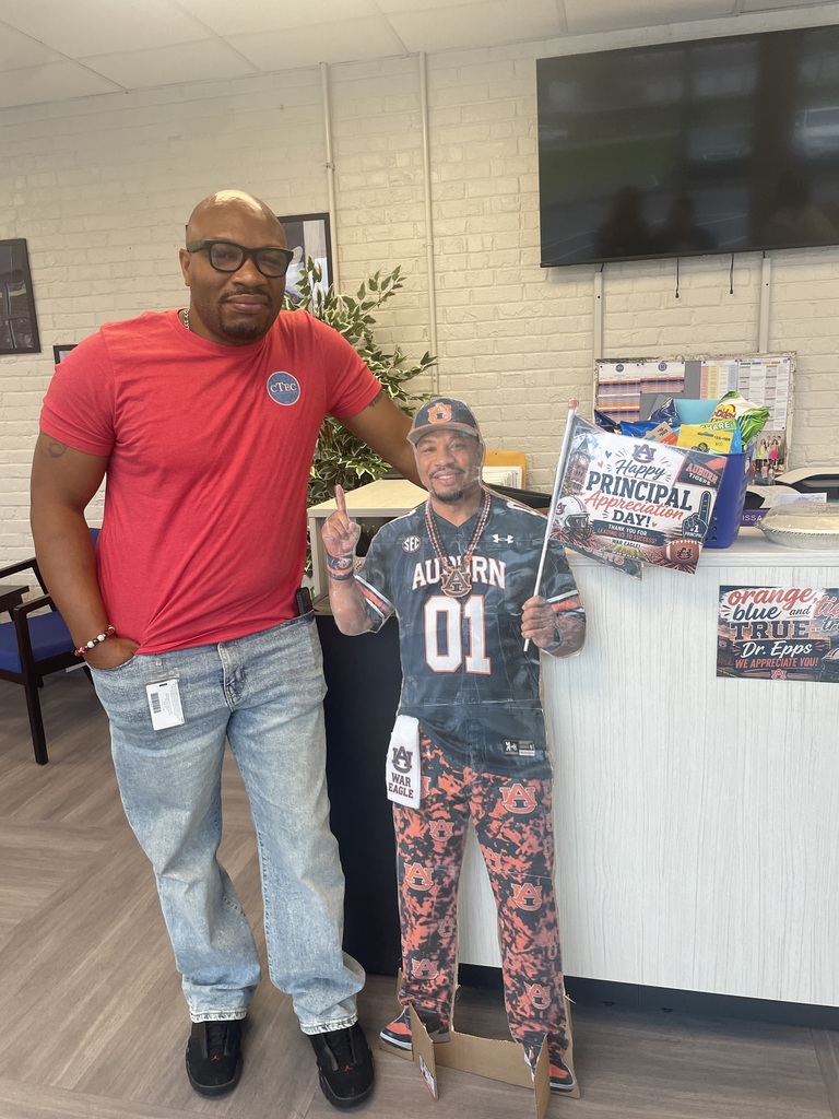Dr. Epps poses with a mini printed version of him dressed in Auburn Fan Gear.