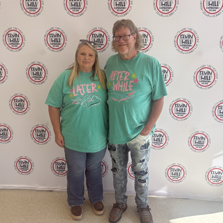 man and woman posed in front of step and repeat backdrop with school logo
