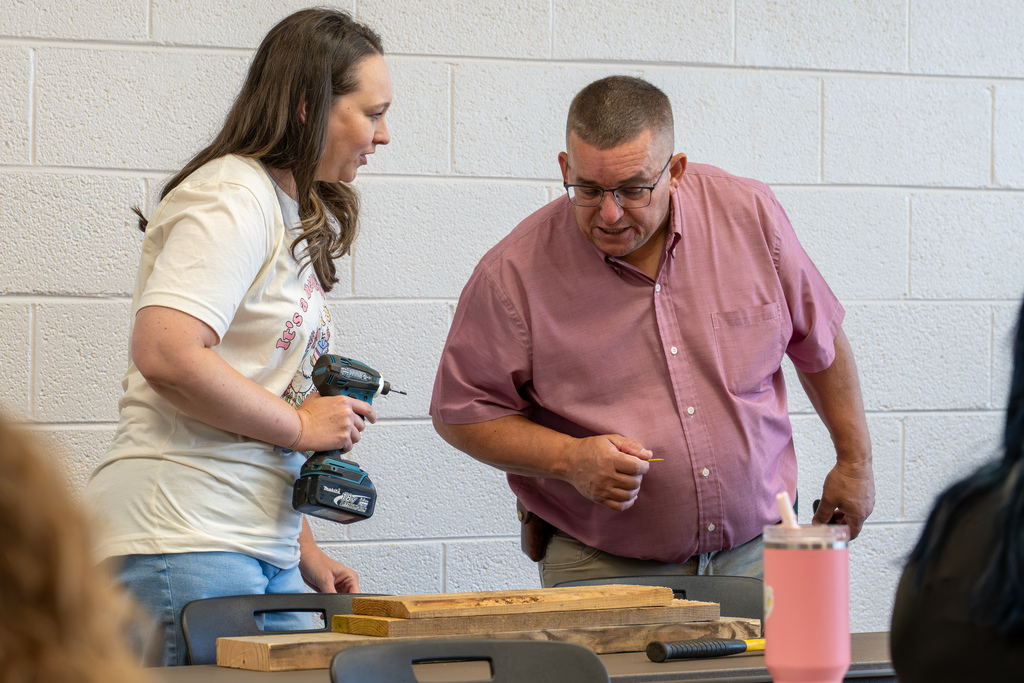 Two educators collaborate on a hands-on activity using woodworking materials during a professional development session.