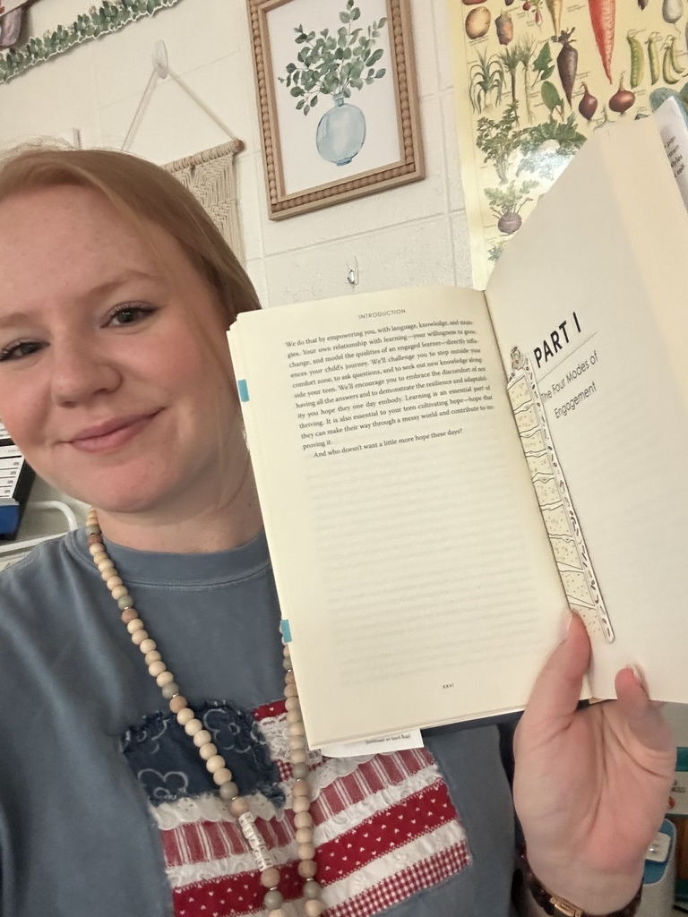 Ms. Boyd holding up a book to the page she is reading 
