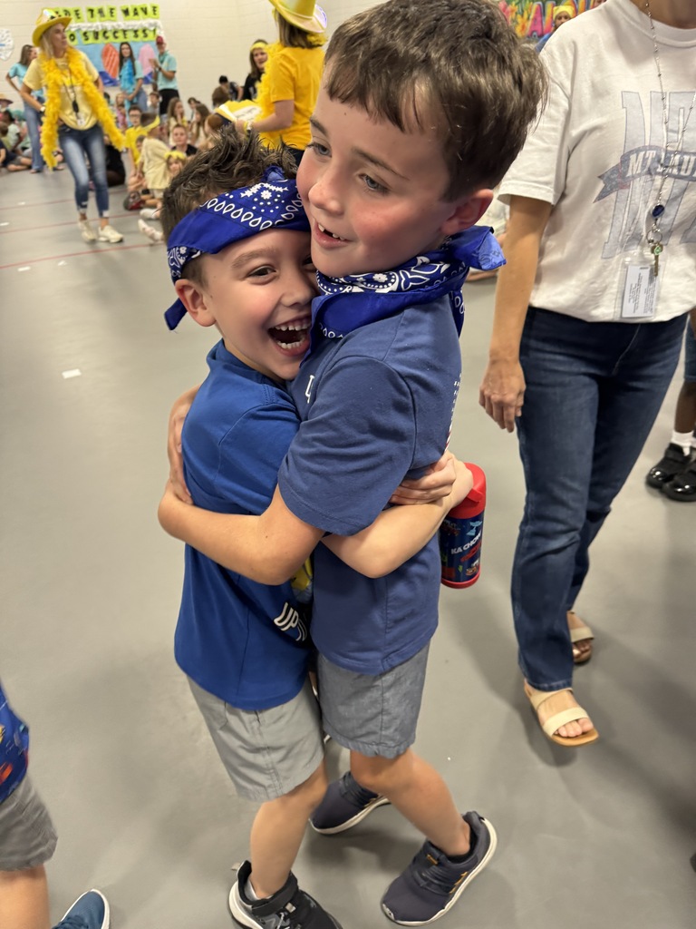 Two boys wearing royal blue bandanas hugging.