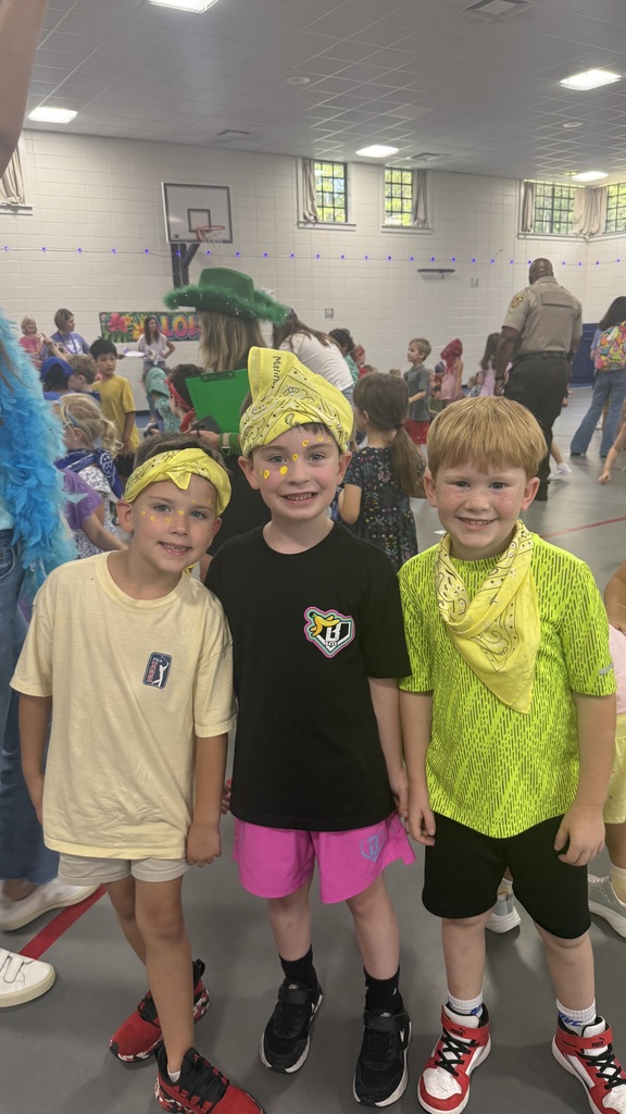 Three boys wearing yellow bandanas smiling for a photo.