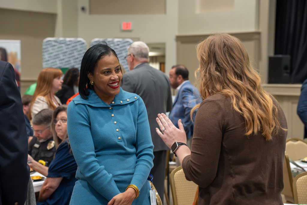 Two women talk and smile during the State of Our Schools event.
