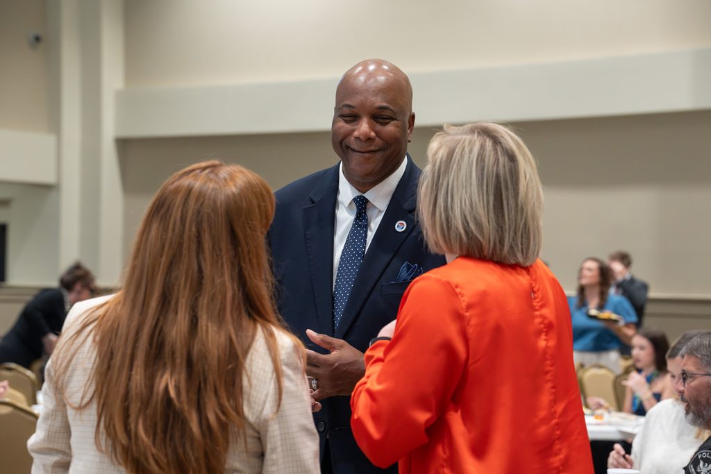 An attendee smiles while talking with two guests at the State of Our Schools event.